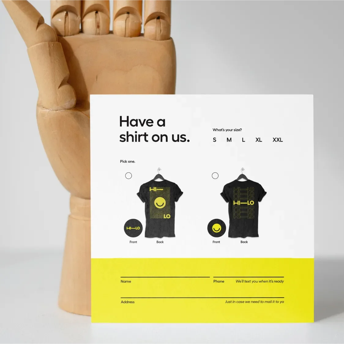 Print t-shirt order form from the Hi-Lo open house propped against a wooden hand