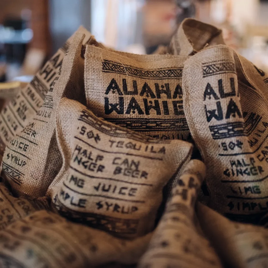 Close-up of pile of cloth sacks containing a cocktail ingredients with the contents screen printed on the front