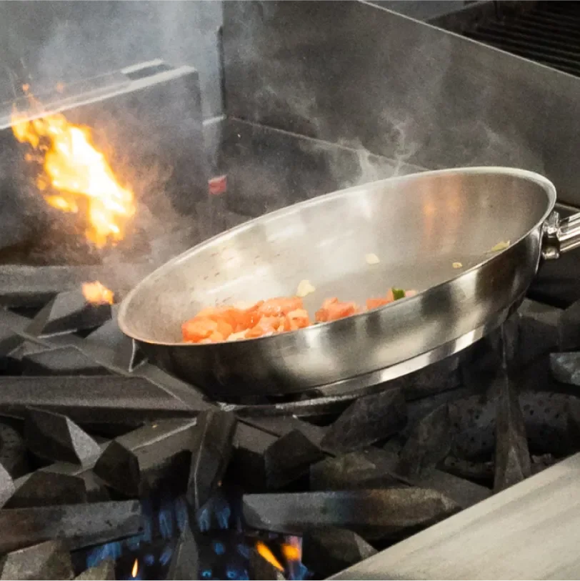 Pan of food being worked on a flaming oven