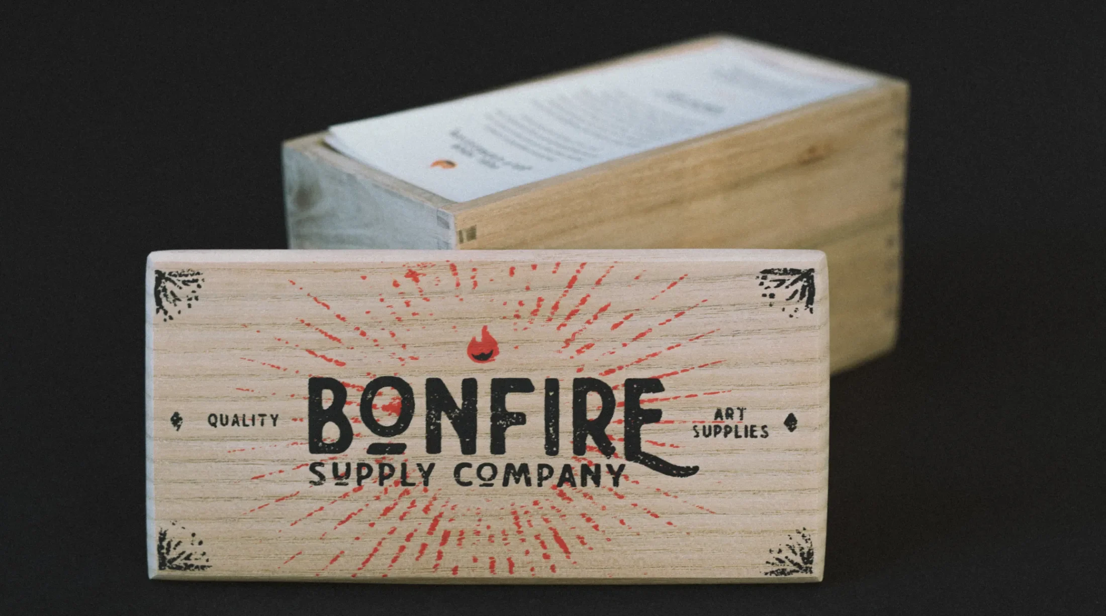 Wooden lid with a Bonfire Supply Company graphic printed on featuring the rest of the bento box in the background