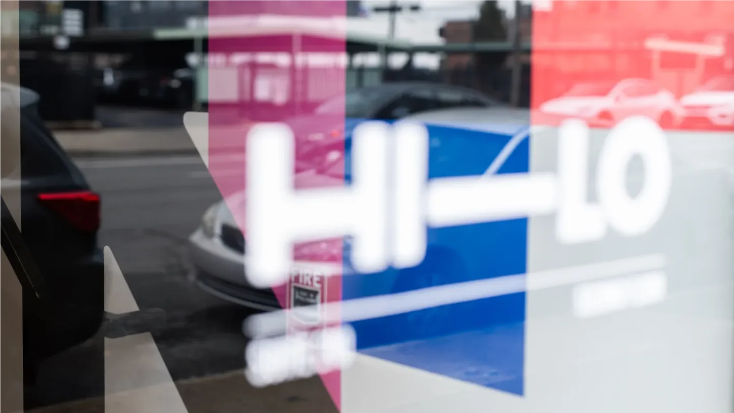 Close-up of the Hi-Lo door sign with a grid of brand colors in the background