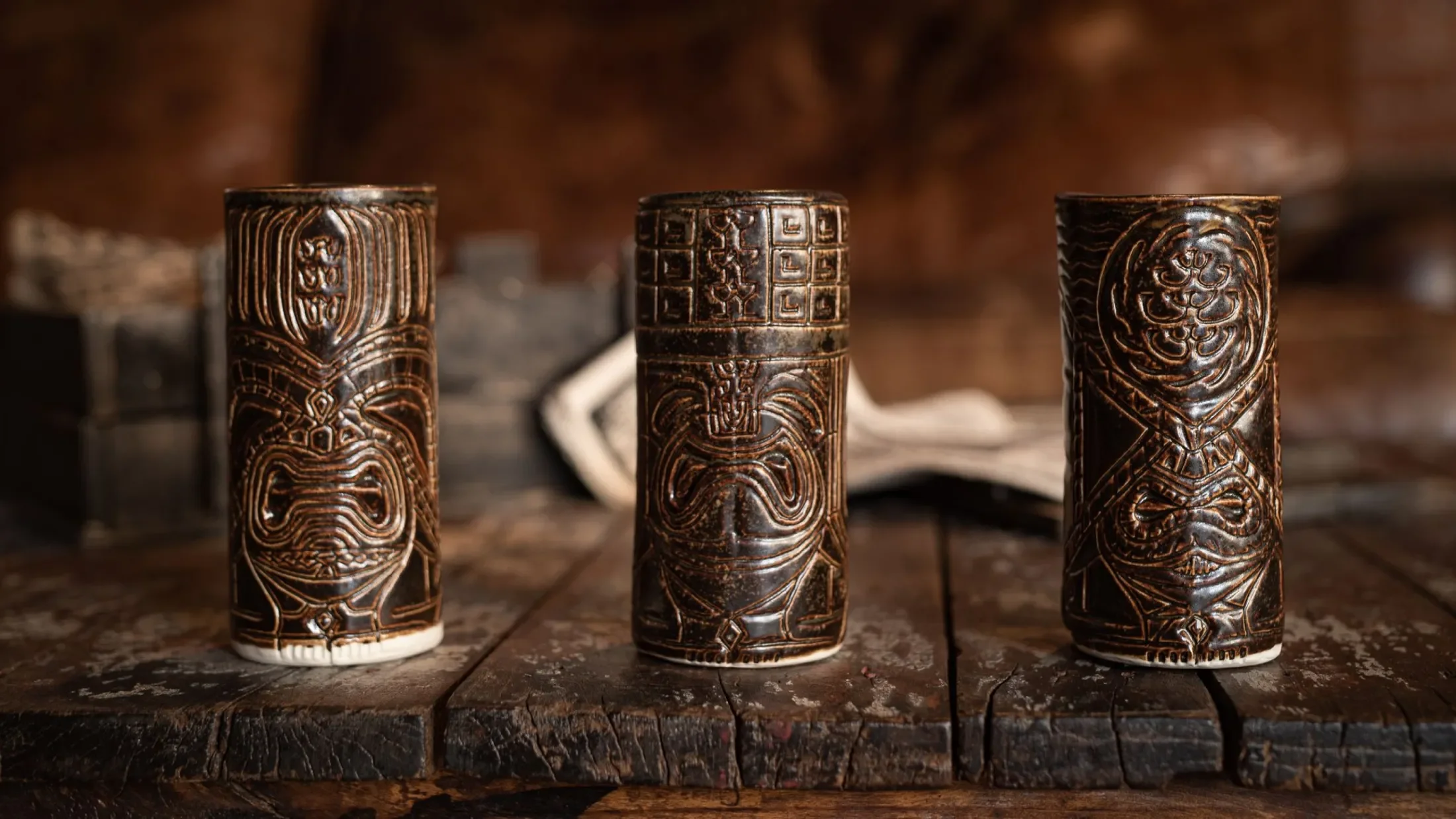 All three tiki mugs facing forward on a wooden table